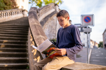 Fototapeta na wymiar Boy involved in reading a book outdoors