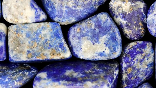 Lapis lazuli heap jewel stones texture on black background. Moving right seamless loop backdrop.