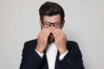 Man suffering from eyestrain on light grey background