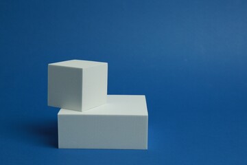Product photography props. Podiums of different geometric shapes on blue background, space for text