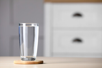 Glass of clean water on wooden table indoors, space for text