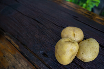 Raw potato diet.  Fresh potatoes on wooden floor . Space for messages . Raw potatoes that can be used in many dishes.