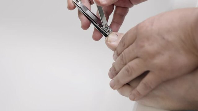 Man cuts his toenails with a nail clipper. Thick foot. Close up shot