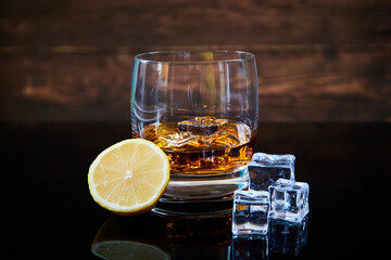 glass of whiskey with ice cubes and lemon