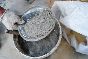men's gloved hands sift through the sand for the cement mortar. 