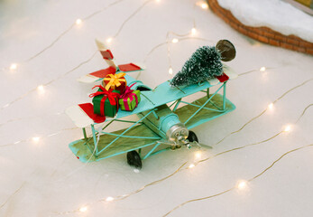 Christmas tree and gift boxes on a blue color vintage airplane toy. Happy holidays concept