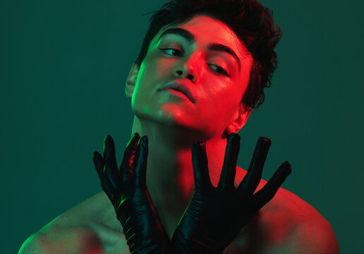Art, neon lights and creative portrait of man with leather gloves, serious face and self expression. Futuristic cyberpunk fashion, topless male model and artistic beauty on green studio background.
