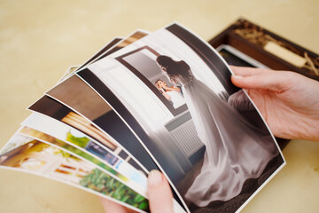 printed wedding photos in the hands and in a wooden box with a flash drive. 