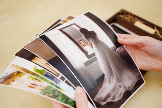 printed wedding photos in the hands and in a wooden box with a flash drive. 