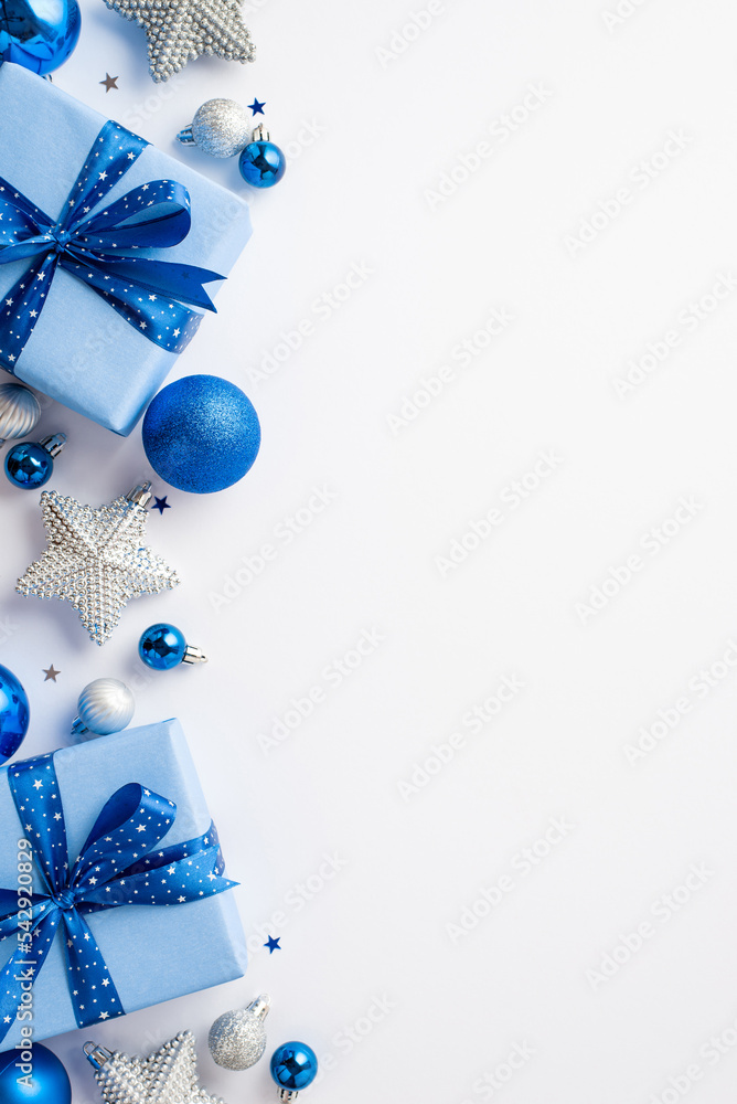 Wall mural New Year concept. Top view vertical photo of present boxes with ribbon bows blue white silver baubles and star ornaments on isolated white background with empty space