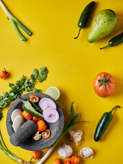 Ingredientes mexicanos en fondo amarillos con molcajete y aguacate