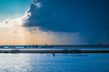 Obraz premium Towards the sunset. Marano lagoon late summer colors. Clouds and sun