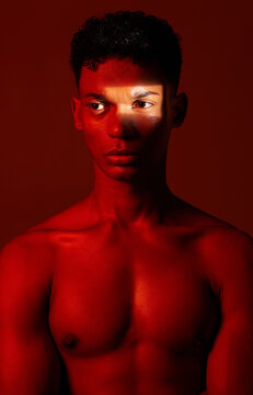 Beauty, red light and man in studio for health, wellness and skincare with a spotlight reflection. Body, self care and healthy male model from Mexico with cosmetics isolated by a red background.