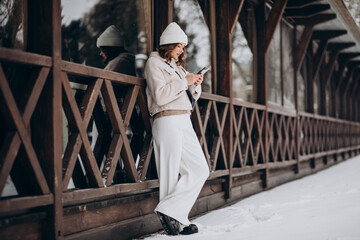 Young woman using phone outside the street at winter time