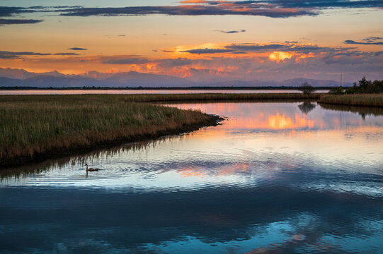 Towards the sunset. Marano lagoon late summer colors. Clouds and sun