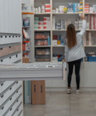 Farmacéutica irreconocible, cogiendo medicinas en el almacén, con cajoneras.