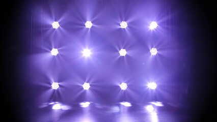 Stage blue lights shine on dark disco. Beams of spotlights illuminating an empty smoky stage in nightclub. Lighting equipment. Light effects. Concept of a holiday, show or theatrical performance.
