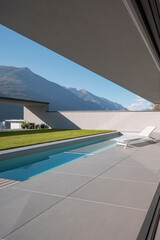 Garden of modern villa with swimming pool and a deck chair for relaxing. Sunny day in the Alps of...
