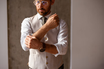 Bearded businessman rolling up sleeve of shirt in office 