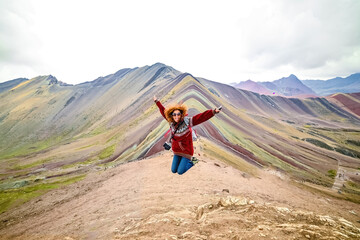 Jong roodharig glimlachend meisje dat voor de Vinicunca Rainbow Mountain, Peru springt