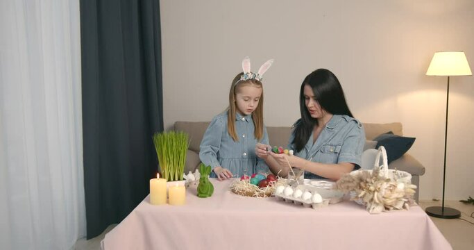 Mother with daughter painting eggs for Easter