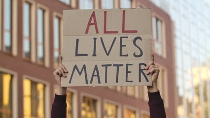 ALL LIVES MATTER on cardboard poster in hands of male protester activist. Stop Racism concept, No Racism. Rallies against racism and police brutality. Peaceful life of blacks matters. Close up.