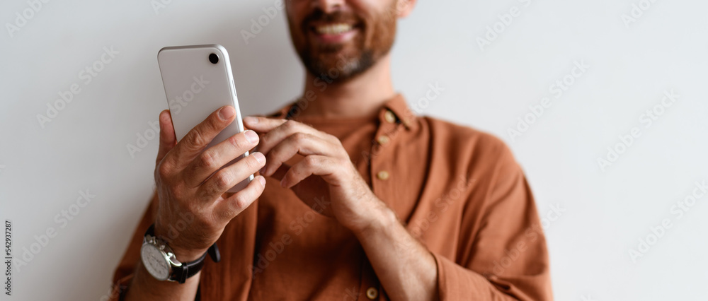 Wall mural partial view of blurred man using mobile phone near wall, banner crop