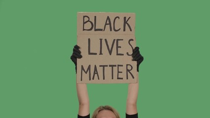 Hands of an unknown person in black gloves raise cardboard poster BLACK LIVES MATTER. Stop Racism concept, No Racism. Peaceful life of blacks matters. Isolated green screen chroma key. © kinomaster