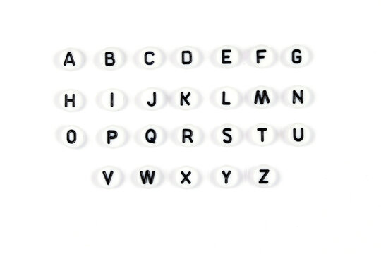 Top view of the English alphabet made of white beads with the English alphabet scattered on a white background with space for text. The concept of the development of thinking, grammar