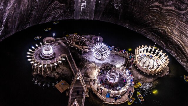 Aerial shot of Salina Turda salt mine the deep underground lake with tourists visiting, in Romania