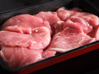 Raw pork chops lying in a baking tray.