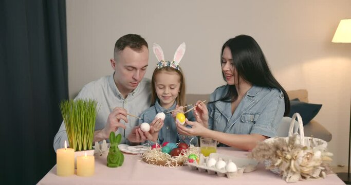 Happy family draw easter eggs together at home