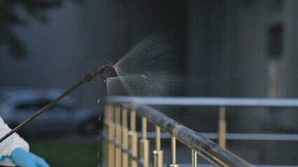 High pressure cleaner spraying alcohol disinfectant spray onto railing surface. Disinfection of...