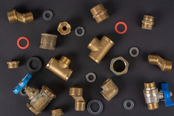 Metal plumbing tees, water pipe adapters on a black background.