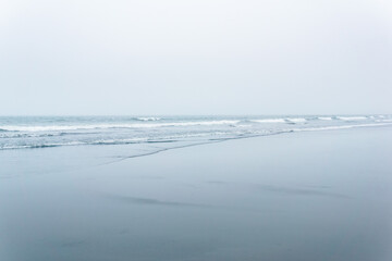 foggy seascape, cold ocean shore with a wide beach