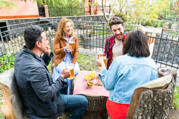 Diverse people friends haging drinking beer outside – happy friends drinking beer at rooftop home terrace – hands holding beer glasses on table