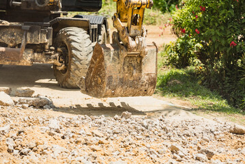 An excavator with a backhoe removes concrete debris from a recently demolished road in a provincial...