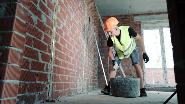 The master throws plaster on the wall. Plastering a brick wall is a task performed by a male craftsman. Master builder plasters brick walls