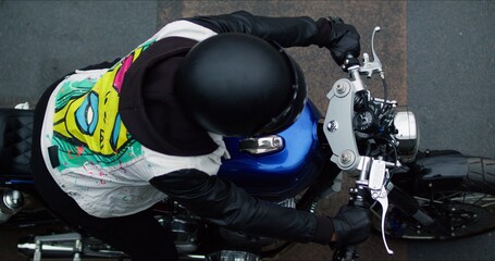 Handsome rider guy sitting on classic style cafe racer motorcycle at day time. Bike custom made in...