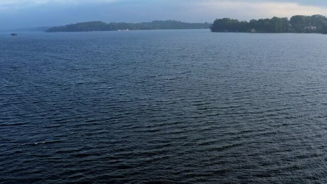 Dolly-out tilting-up aerial drone shot of the stunning man-made Guarapiranga Reservoir in the south of S&atilde;o Paulo, Brazil with calm waters, beaches, marinas, and wildlife on an overcast fall evening.