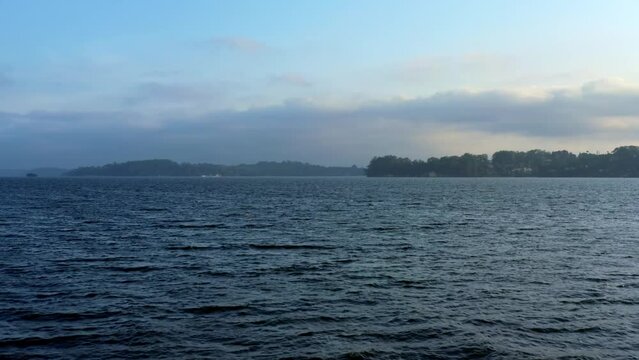 Ascending dolly-in aerial drone shot of the stunning man-made Guarapiranga Reservoir in the south part of S&atilde;o Paulo, Brazil with calm waters, beaches, marinas, and wildlife on an overcast fall evening