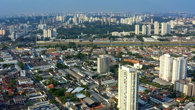 Aerial drone tilting up dolly-in shot of the south part of S&atilde;o Paulo, Brazil from the Socorro neighborhood near the Guarapiranga Reservoir with skyscrapers, roads, rivers, and houses on a fall evening
