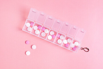 Beautiful closeup of tablet vitamin for women on pink background . Medical healthcare pillbox for a week. Medicine medical health. 