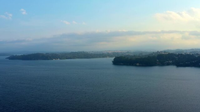 Beautiful ascending aerial drone shot of the stunning man-made Guarapiranga Reservoir in the south part of S&atilde;o Paulo, Brazil with beaches, marinas, and wildlife on a fall foggy evening.