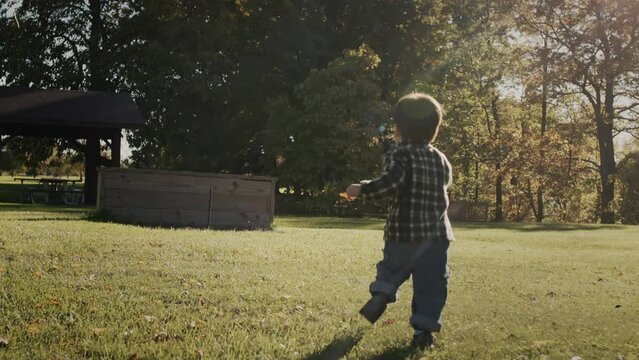 An active kid runs through a green meadow on a clear autumn day.