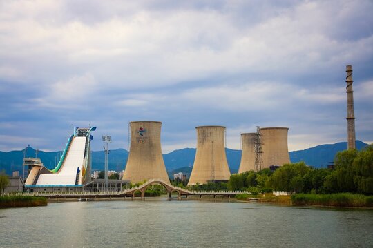 Coal Power Station Towers In Shougang Park By The Water Under Cloudy Sky