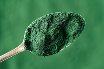 Top view of green spirulina algae powder on a spoon