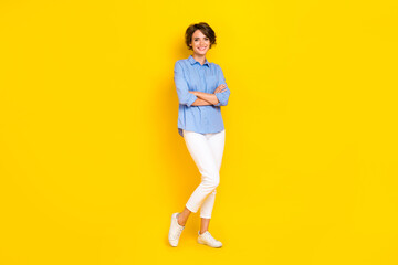 Fototapeta na wymiar Full length photo of cheerful positive lady wear blue shirt arms crossed smiling isolated yellow color background