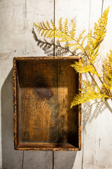 Vintage wood box on white wood surface with yellow fern