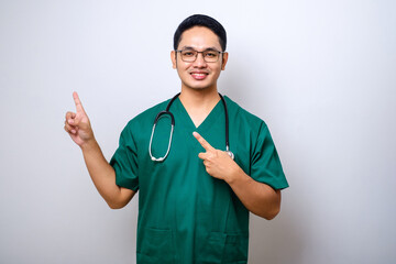 Smiling handsome asian doctor, nurse in scrubs and stethoscope, pointing fingers upper left corner, showing online clinic banner